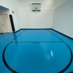 Indoor basketball court featuring floor coating in assembly blue, black game lines, Gladiator 60" fixed basketball hoop, black corner pad, black cove base
